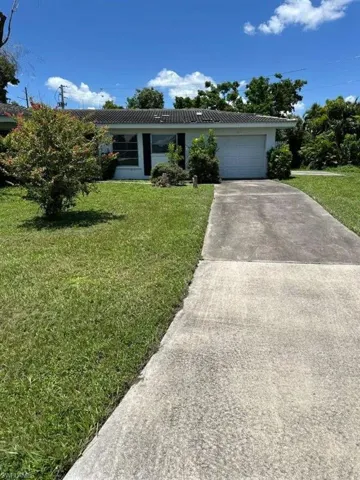 Ranch-style house featuring a garage and a front lawn