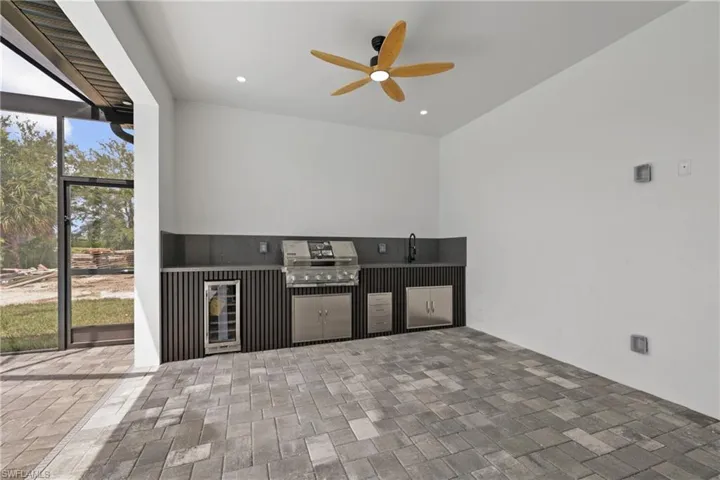 View of patio / terrace with exterior kitchen, ceiling fan, beverage cooler, and glass enclosure