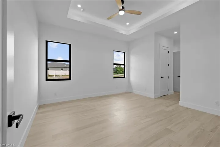 Empty room featuring recessed lighting, light wood-type flooring, a raised ceiling, and ceiling fan