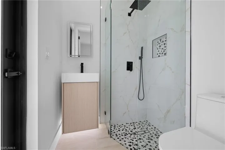 Full bathroom with a marble finish shower, vanity, and light tile patterned floors