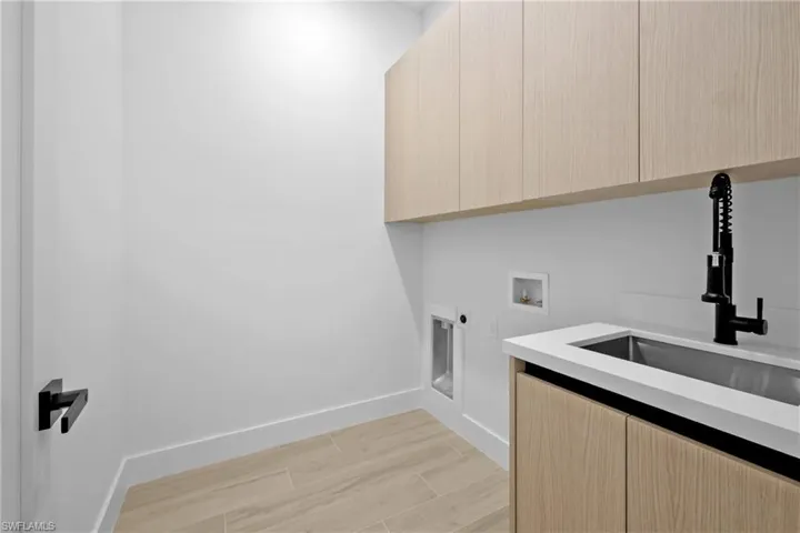 Laundry room featuring wood finish floors, hookup for a washing machine, cabinet space, and hookup for an electric dryer