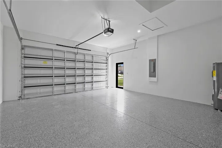 Garage with water heater, electric panel, and a garage door opener