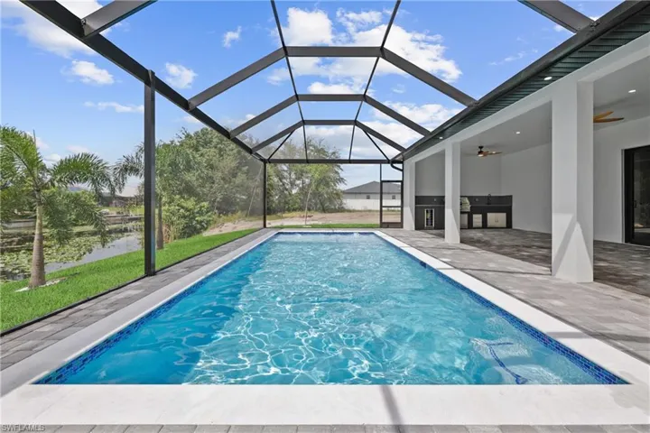 Swimming pool with exterior kitchen, a sunroom, ceiling fan, a lanai, and a patio
