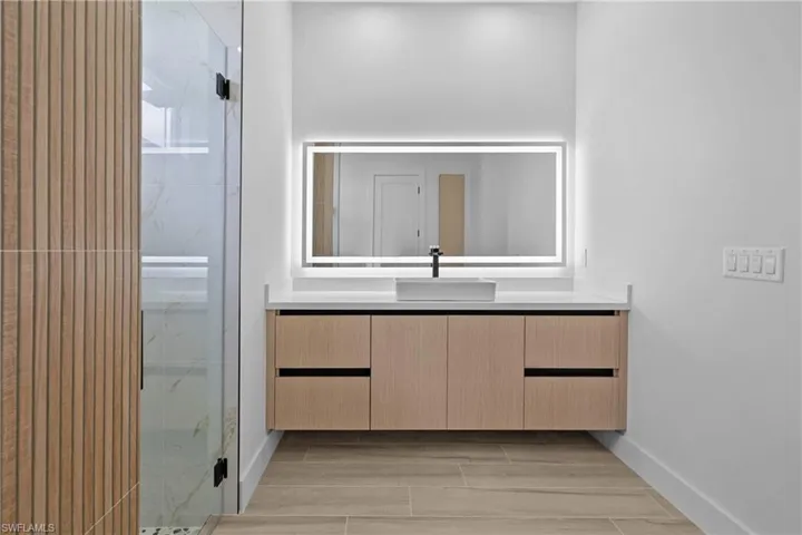 Bathroom featuring vanity, a marble finish shower, and wood finish floors