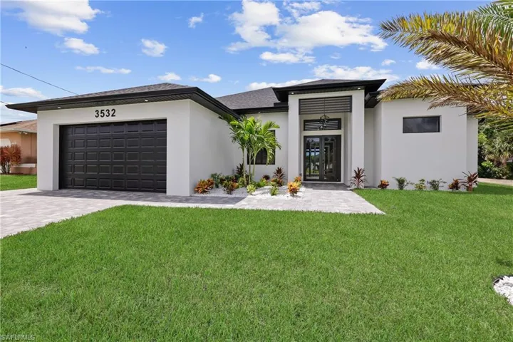 Prairie-style home with stucco siding, a front lawn, decorative driveway, and an attached garage