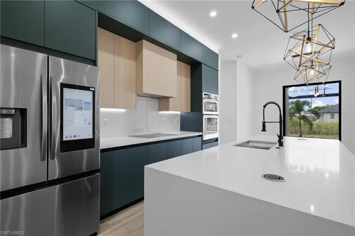 Kitchen with stainless steel appliances, modern cabinets, a center island with sink, pendant lighting, and recessed lighting