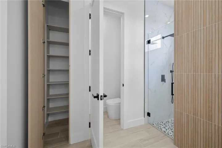 Full bathroom with a marble finish shower and a closet