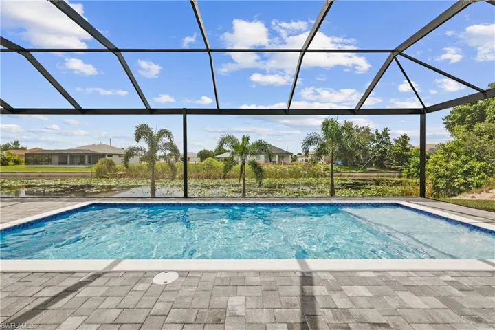 Swimming pool featuring a sunroom, a water view, glass enclosure, and a residential view