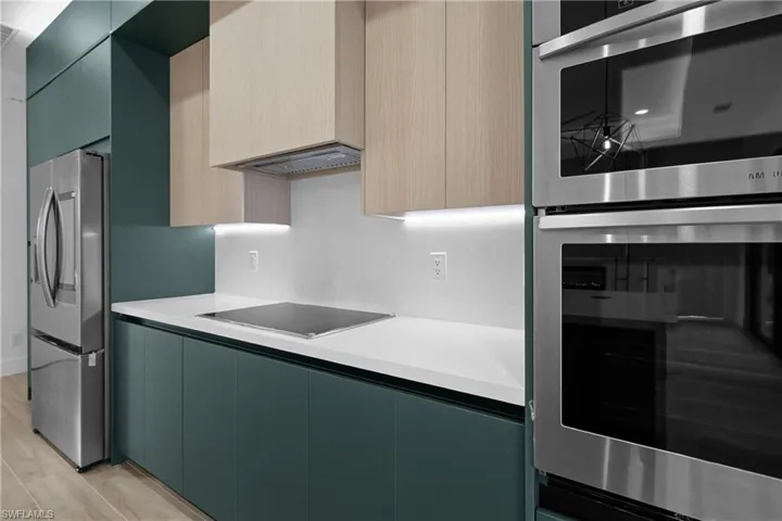 Kitchen with modern cabinets, stainless steel appliances, light wood finished floors, and light stone countertops