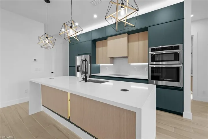 Kitchen featuring light brown cabinetry, modern cabinets, hanging light fixtures, wood finish floors, and recessed lighting