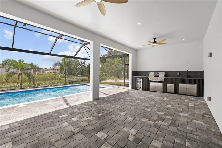 Swimming pool featuring area for grilling, ceiling fan, a patio, glass enclosure, and a sunroom