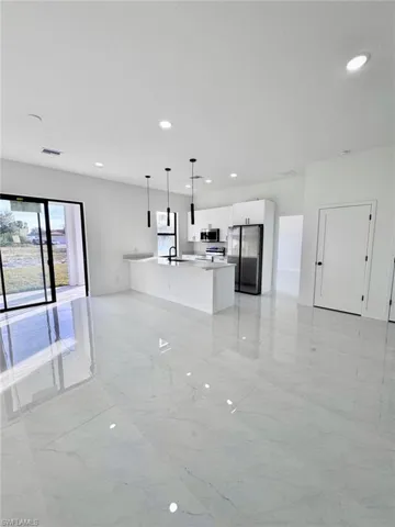 Kitchen featuring open floor plan, white cabinetry, hanging light fixtures, and stainless steel appliances
