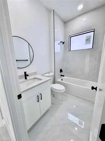 Full bathroom with bathtub / shower combination, vanity, light marble finish floors, and recessed lighting