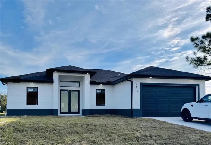 View of front of house with a front lawn, roof with shingles, a garage, and stucco siding