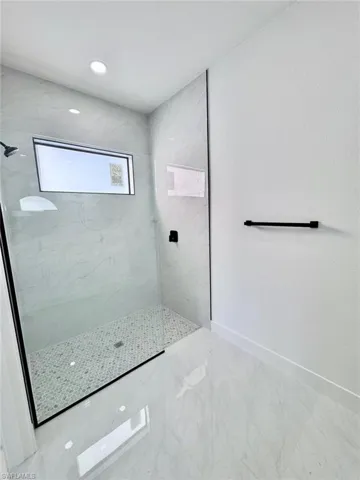 Bathroom featuring a marble finish shower, light marble finish flooring, and recessed lighting