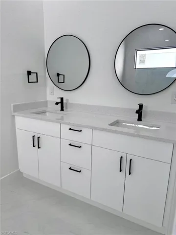Bathroom with double vanity and light marble finish floors