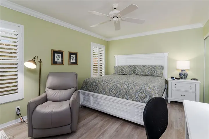 Second Primary Bedroom with crown molding, plantation shutters laminate flooring, and a ceiling fan