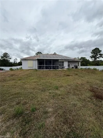 Rear view of property with a lawn, a sunroom, and stucco siding