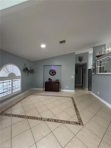 Unfurnished living room featuring light tile patterned floors, inlaid floor details, lofted ceiling, recessed lighting, and a textured ceiling