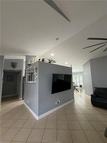 Living area featuring light tile patterned flooring, a ceiling fan, and recessed lighting