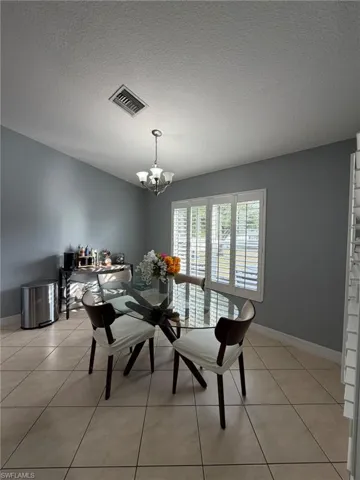 Dining area with a textured ceiling, a chandelier, and light tile patterned floors