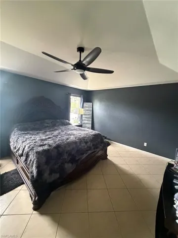 Bedroom with ceiling fan and light tile patterned flooring