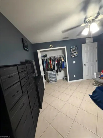 Bedroom featuring light tile patterned flooring, a ceiling fan, and a closet
