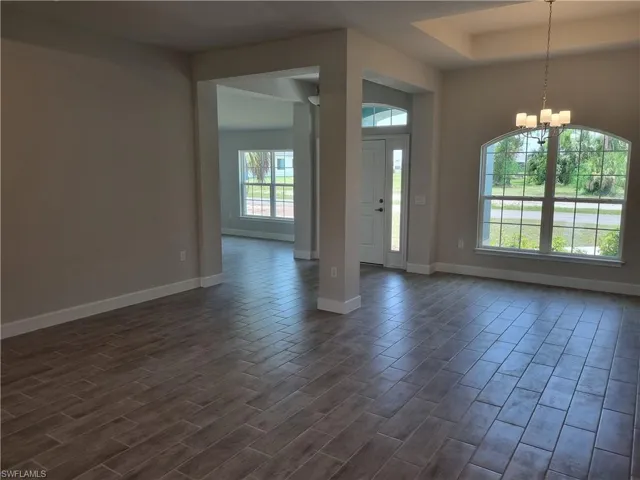 Entryway featuring dark wood-style floors, a chandelier, and a tray ceiling