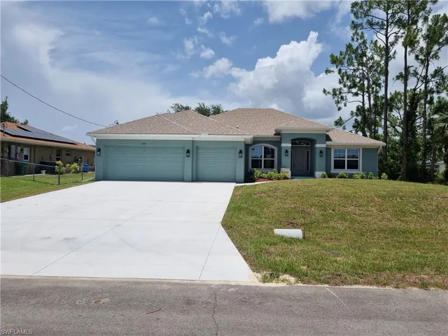 View of front of home with a garage, driveway, a front yard, stucco siding, and a shingled roof