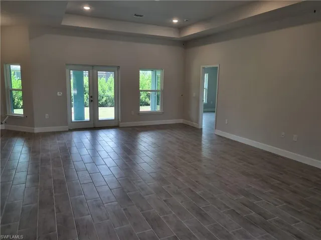Unfurnished room featuring a tray ceiling, recessed lighting, dark wood finished floors, and french doors