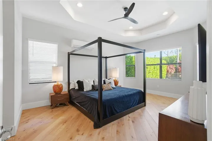 Bedroom featuring a raised ceiling, light wood-style floors, ceiling fan, and recessed lighting