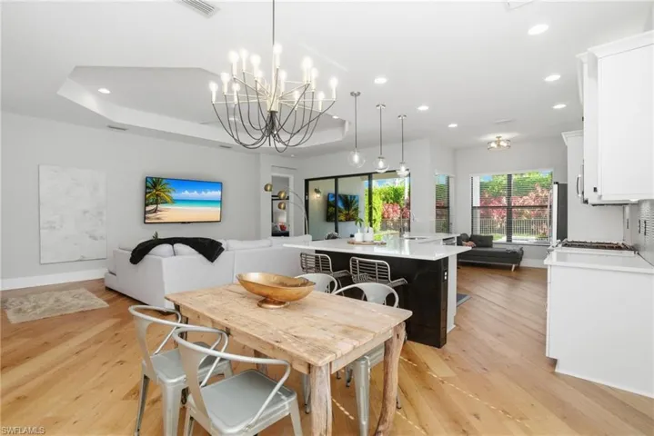 Dining area featuring light wood-type flooring, recessed lighting, a raised ceiling, and a chandelier