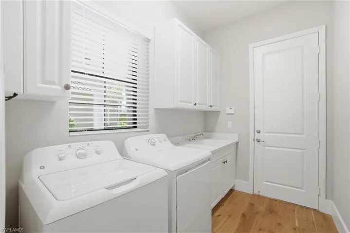 Laundry room featuring independent washer and dryer, cabinet space, and light wood-type flooring
