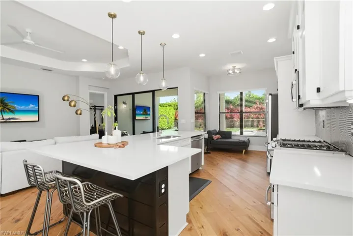 Kitchen with open floor plan, a breakfast bar, a spacious island, light wood-style floors, and white cabinets