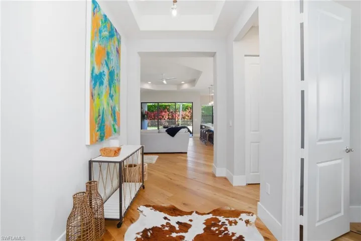 Hall with a raised ceiling and light wood finished floors