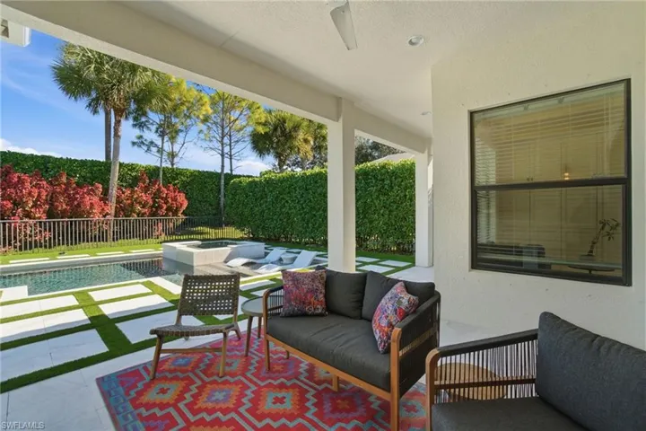 Fenced backyard featuring a patio area, ceiling fan, outdoor seating, and a pool with connected hot tub