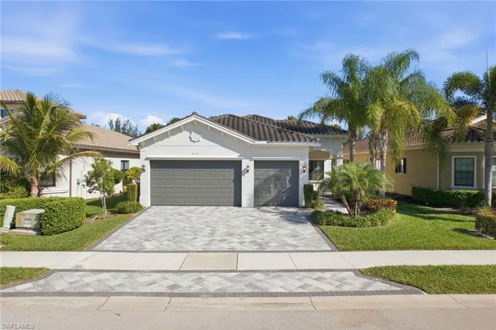 Mediterranean / spanish-style house with stucco siding, decorative driveway, a front lawn, and an attached garage