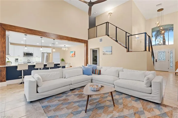 Tiled living room featuring a towering ceiling and ceiling fan with notable chandelier