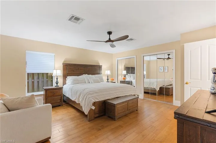 Bedroom with light wood-type flooring, ceiling fan, and multiple closets
