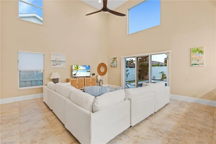 Living room with ceiling fan, plenty of natural light, and a towering ceiling
