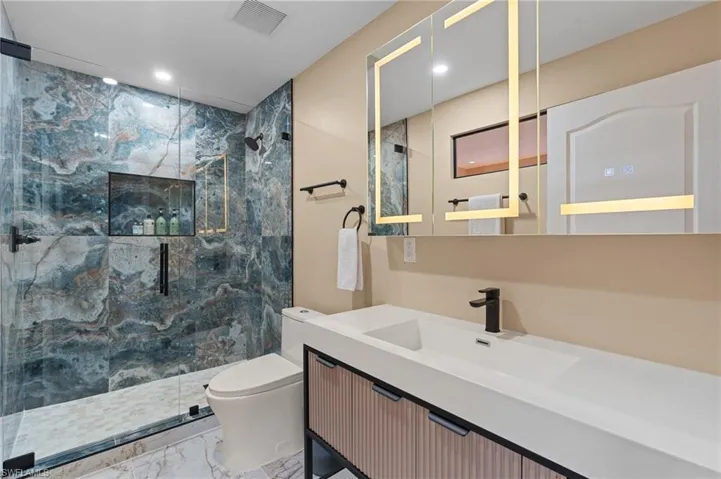 Bathroom featuring vanity, toilet, and a shower with shower door