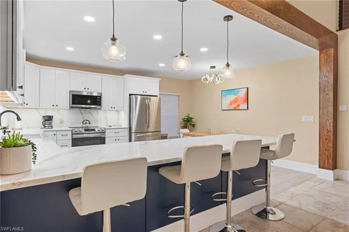 Kitchen featuring sink, decorative backsplash, decorative light fixtures, white cabinetry, and stainless steel appliances