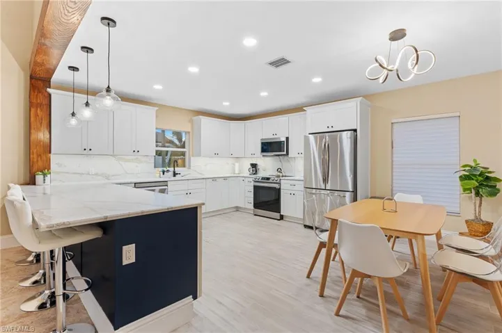 Kitchen featuring white cabinets, appliances with stainless steel finishes, and pendant lighting