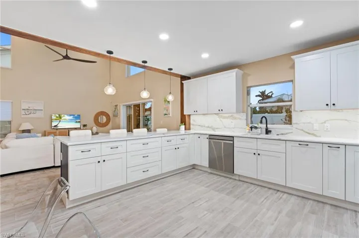 Kitchen with kitchen peninsula, tasteful backsplash, stainless steel dishwasher, pendant lighting, and white cabinets