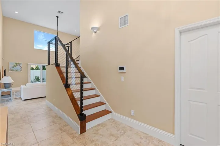 Stairs with tile patterned floors and a towering ceiling