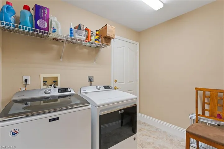 Clothes washing area with light tile patterned floors and washing machine and clothes dryer