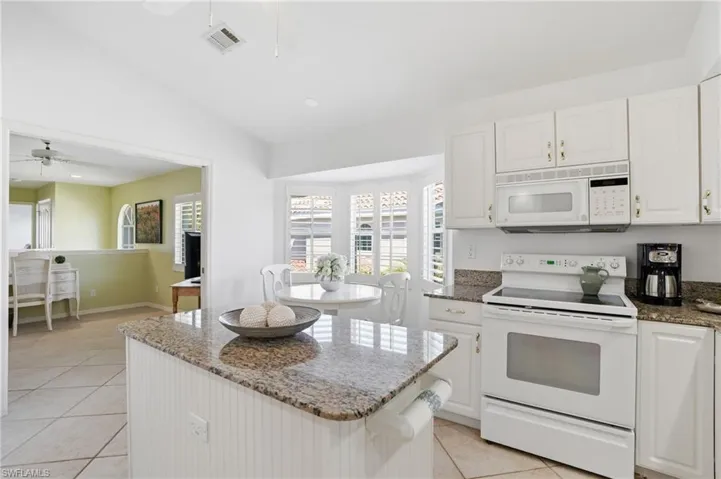 Kitchen featuring white cabinetry, granite-finish countertops, and an eat-in area with a bay window