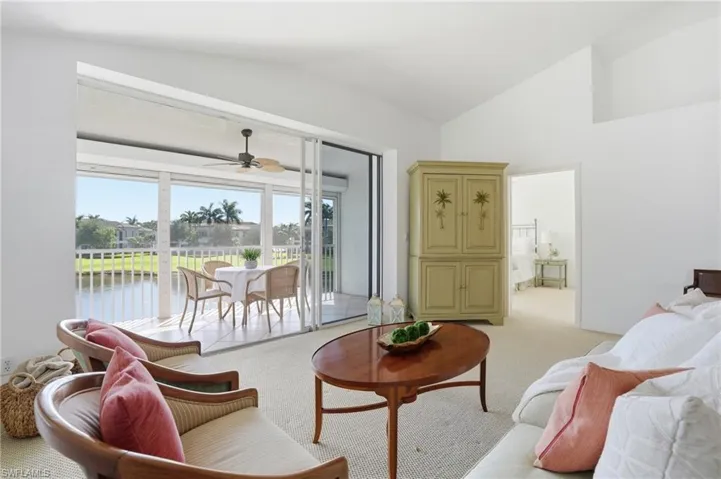 Spacious living area featuring neutral carpeting and vaulted ceilings