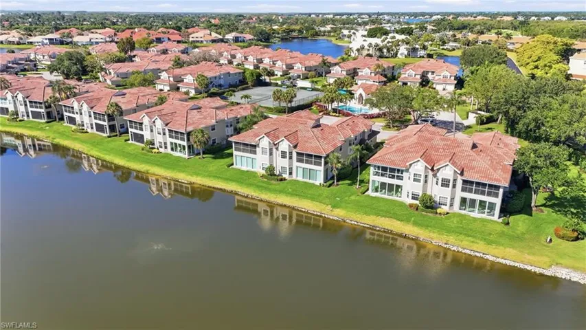 Waterfront community featuring multi-story residences with red tile roofs, screened lanais, and mature landscaping