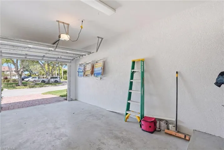 Attached single-car garage featuring a concrete floor, textured wall finish, and an automatic garage door opener